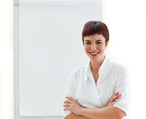 stock image Young businesswoman with folded arms in front of a board