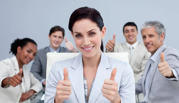 Businesswoman and her team with thumbs up in a meeting — Zdjęcie stockowe