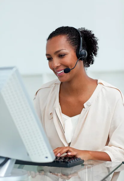 Vrolijke zakenvrouw met hoofdtelefoon op werkt op een computer — Stockfoto