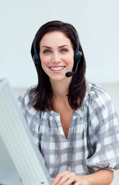 Säker affärskvinna med hörlurarna på arbetar på en dator — Stockfoto