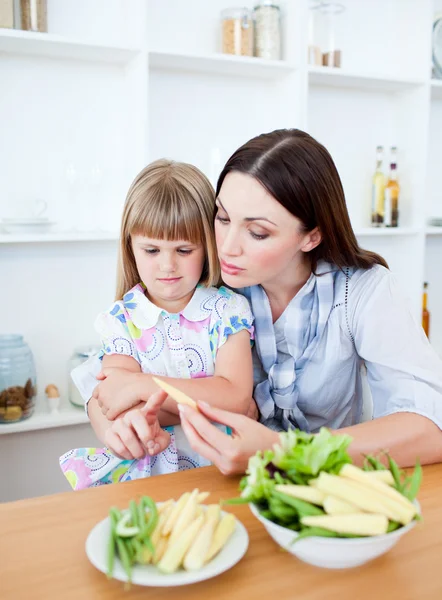 Niezadowolona dziewczynka jedzenie warzyw z matką — Zdjęcie stockowe