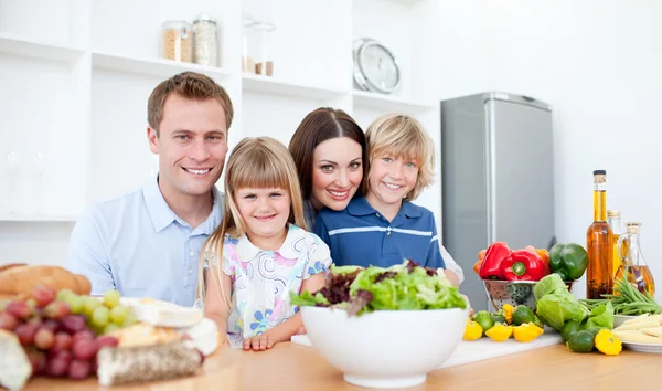 Pais sorridentes e seus filhos preparando o jantar juntos — Fotografia de Stock