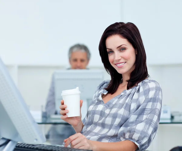Femme d'affaires rayonnante tenant une tasse à boire à son bureau — Photo