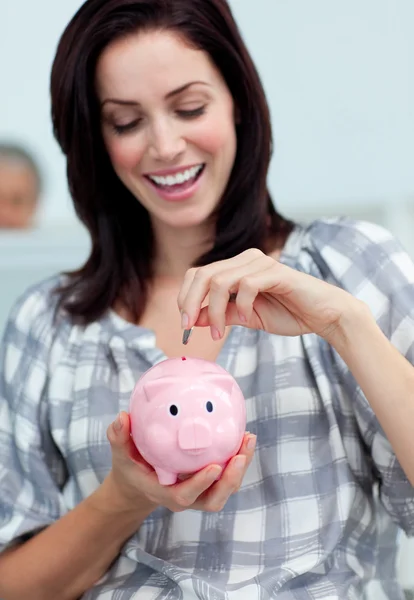 Vrolijke zakenvrouw geld te besparen in een piggy-bank — Stockfoto