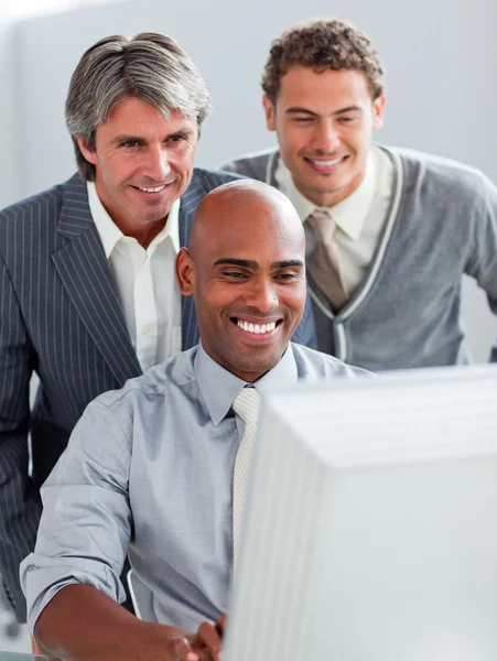 Empresarios positivos ayudando a su colega en una computadora — Foto de Stock