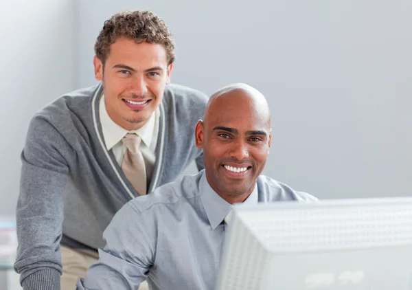 Jovem empresário ajudando seu colega em um computador — Fotografia de Stock