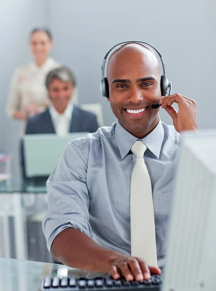 Etnische zakenman werkt op een computer met hoofdtelefoon op — Stockfoto