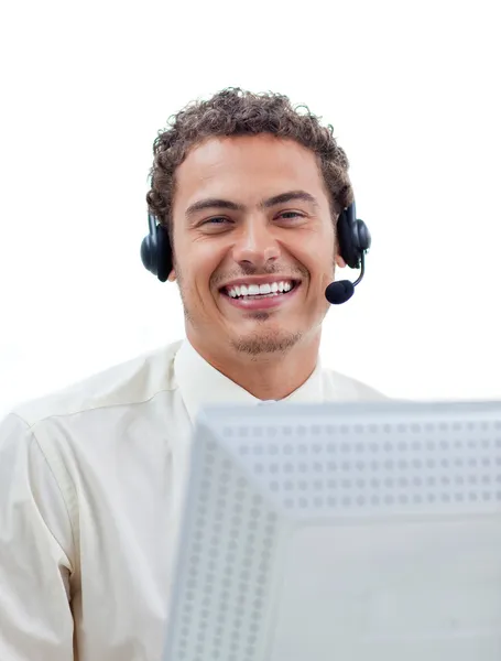 Hombre de negocios positivo hablando con auriculares en una computadora — Foto de Stock