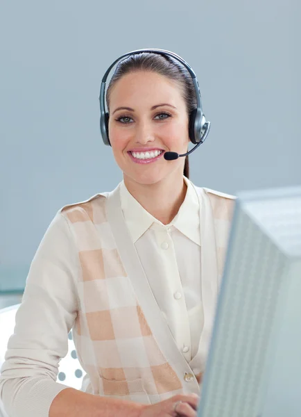 Charmante zakenvrouw met hoofdtelefoon op werkt op een computer — Stockfoto