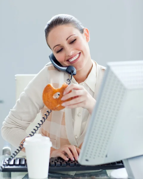 Confident businesswoman on phone eating a donnut — Stock Photo, Image