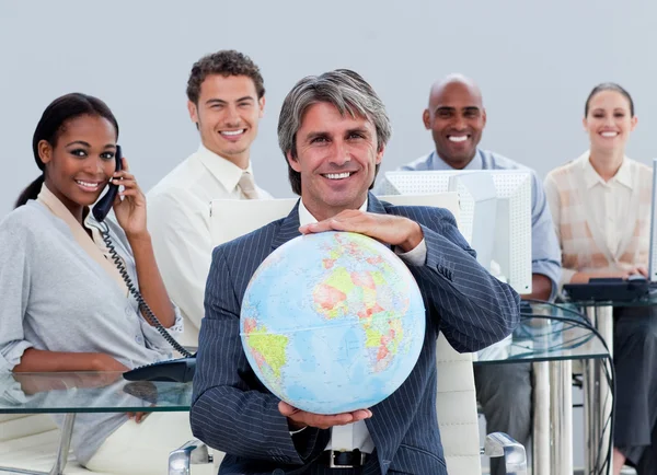 Equipe de negócios feliz no trabalho mostrando um globo terrestre — Fotografia de Stock