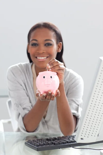 Lachende etnische zakenvrouw geld te besparen in een spaarpot — Stockfoto