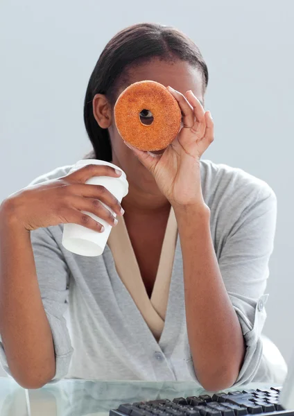 Junge Geschäftsfrau isst einen Donut auf ihrem Schreibtisch — Stockfoto
