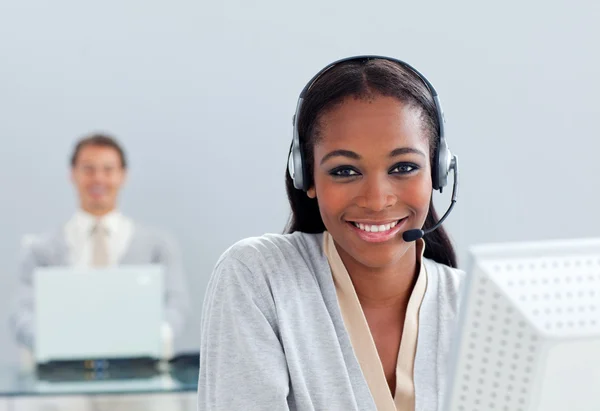 Mujer de negocios sonriente usando auriculares en su escritorio —  Fotos de Stock