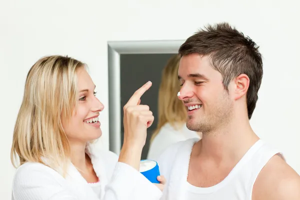 Wife putting cream on his husband's nose — Stock Photo, Image