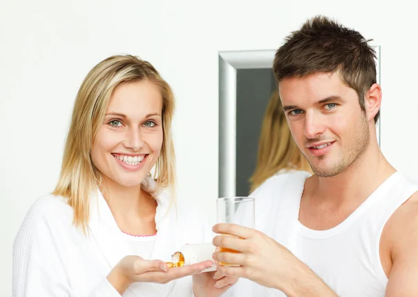 Женщина с таблетками и мужчина со стаканом апельсинового сока — стоковое фото
