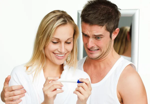 Mulher feliz e homem assustado examinando um teste de gravidez — Fotografia de Stock