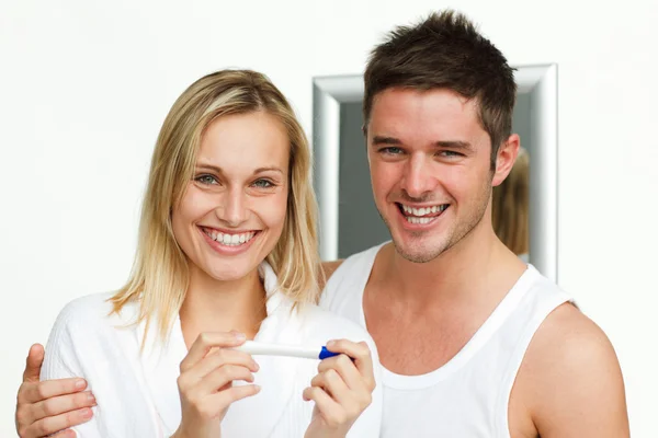 Ευτυχισμένο ζευγάρι που εξετάζει ένα τεστ εγκυμοσύνης που χαμογελά στη φωτογραφική μηχανή — Φωτογραφία Αρχείου