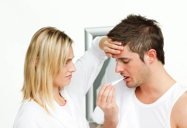 Worried woman examining a man with a termomether — Stock Photo, Image