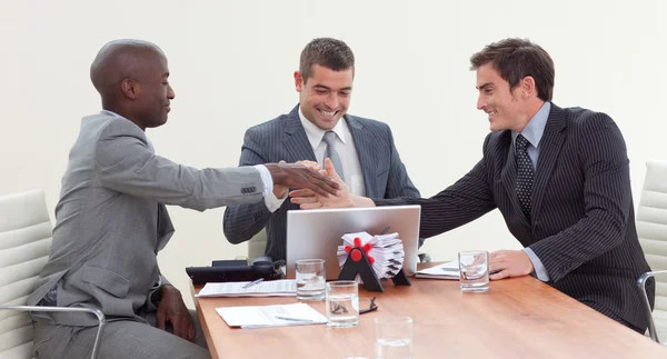 Hombres de negocios felices en una reunión mirando un portátil — Foto de Stock