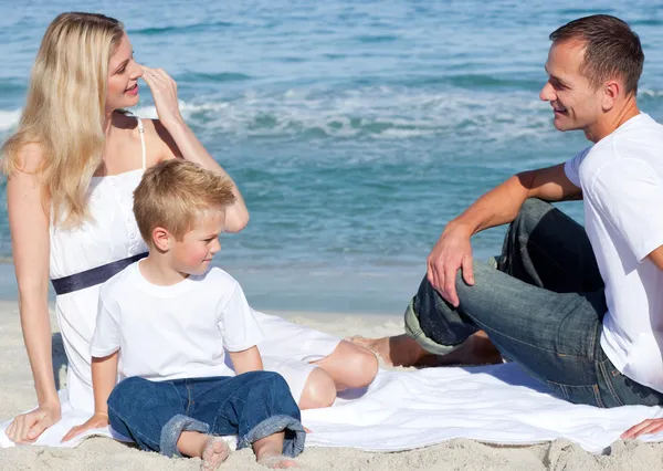 Genitori sorridenti con il figlio seduto sulla sabbia — Foto Stock