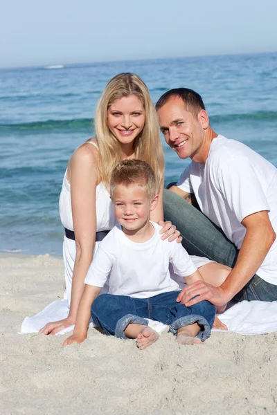 Portret van vrolijke ouders met hun zoon zittend op het zand — Stockfoto