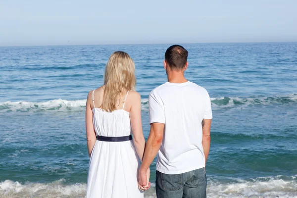 Förälskad par hålla händer vid shore line — Stockfoto