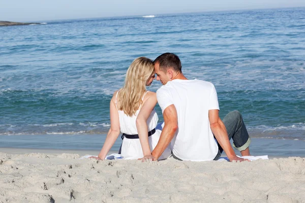 Älskare sitter på sanden — Stockfoto