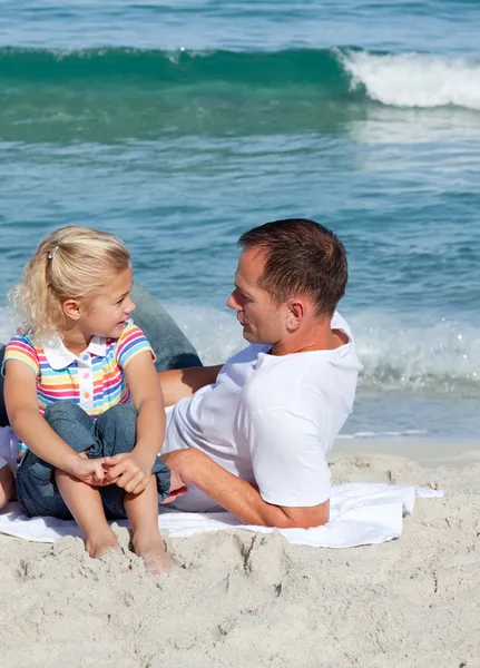 可爱的小女孩和她的父亲坐在沙滩上 — 图库照片