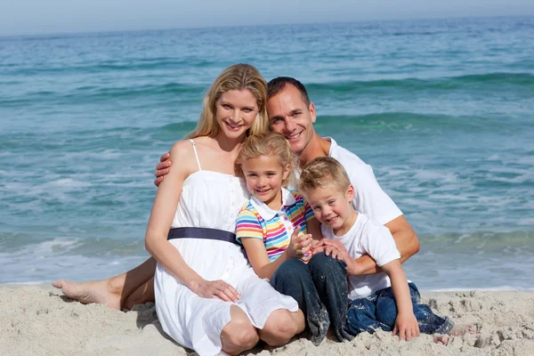 Retrato de una familia alegre sentada en la arena —  Fotos de Stock