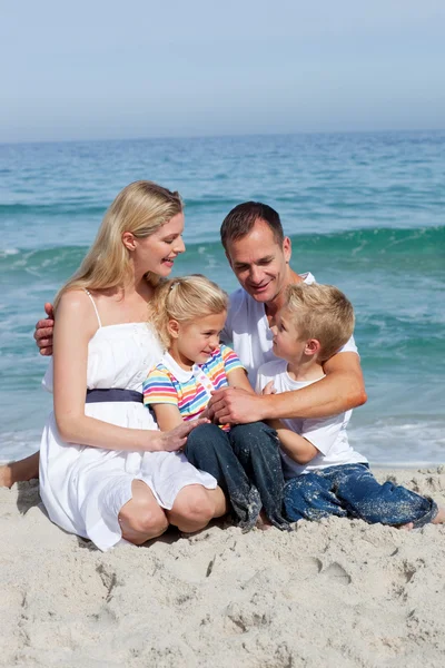 Retrato de uma família afetuosa sentada na areia — Fotografia de Stock