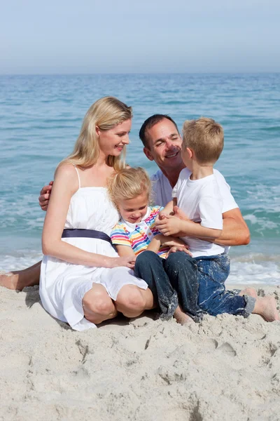 可爱的儿童和他们的父母坐在沙滩上 — 图库照片