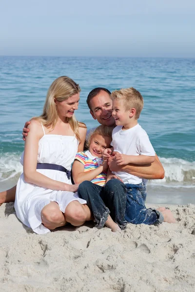 快乐的孩子和他们的父母坐在沙滩上 — 图库照片