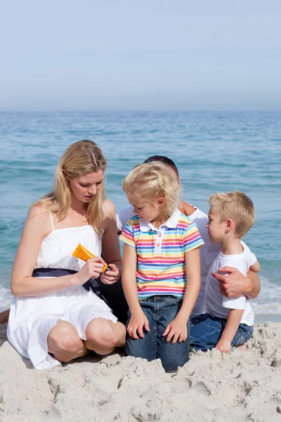 Mãe atenta segurando protetor solar na praia — Fotografia de Stock