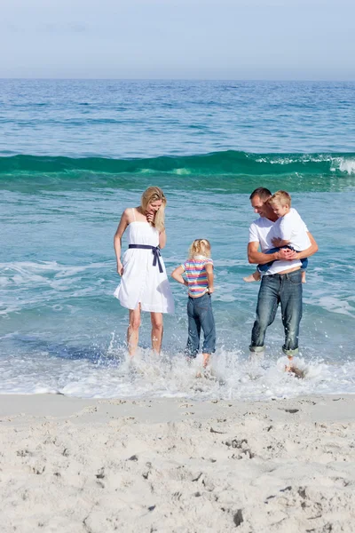 Familia alegre divirtiéndose en la playa — Foto de Stock