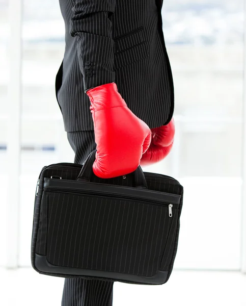 Close-up of a businessman holding a briefcase with boxing gloves