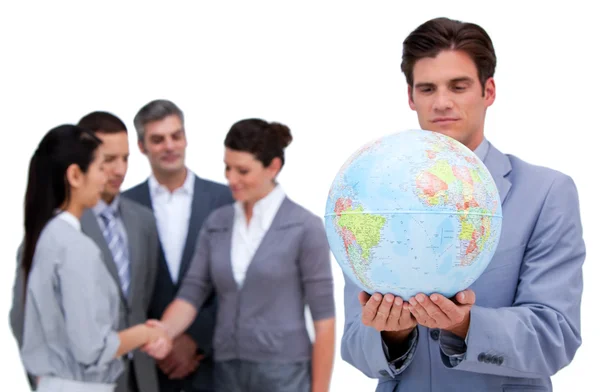 Hombre de negocios guapo y su equipo mirando un globo terrestre —  Fotos de Stock