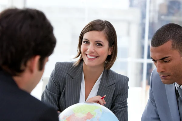 Gelukkig businessteam kijken naar een terrestrische globe — Stockfoto