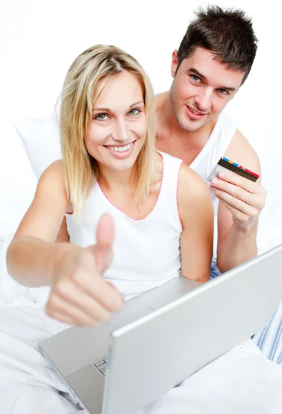 Couple in bed buying on-line with thumb up — Stock Photo, Image
