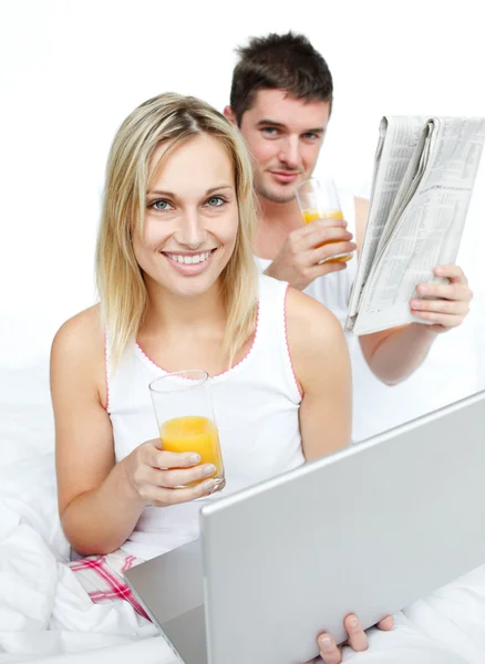 Pareja bebiendo jugo de naranja y leyendo noticias en la cama —  Fotos de Stock