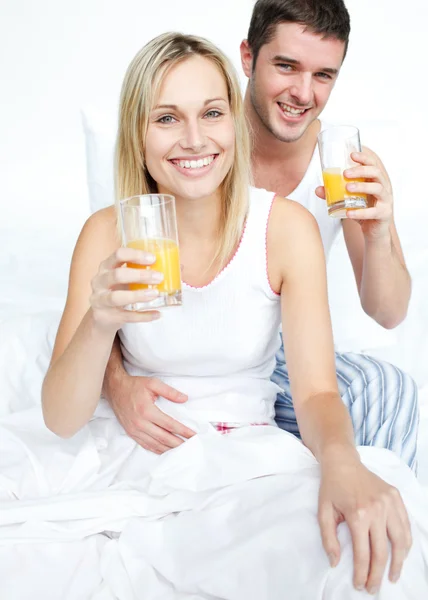 Boyfriend and girlfriend drinking orange juice in bed — Stock Photo, Image