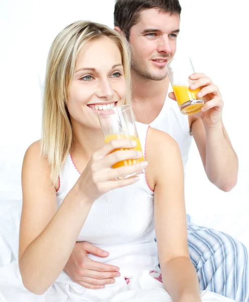 Lovers drinking orange juice in bed — Stock Photo, Image