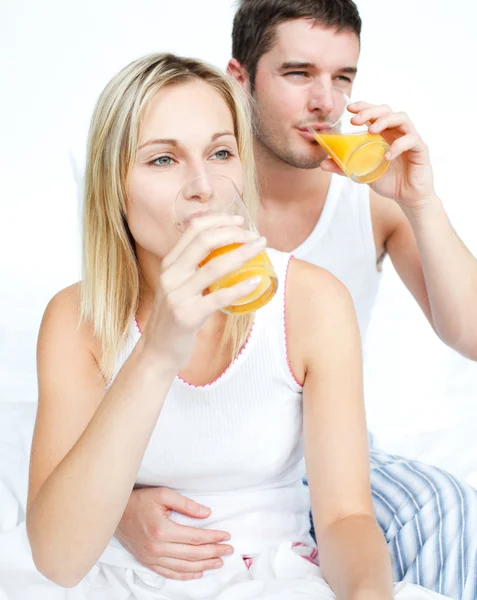 Couple drinking orange juice in bed — Stock Photo, Image