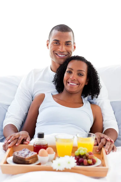 Afro-american couple having breakfast lying on their bed — Stock Photo, Image