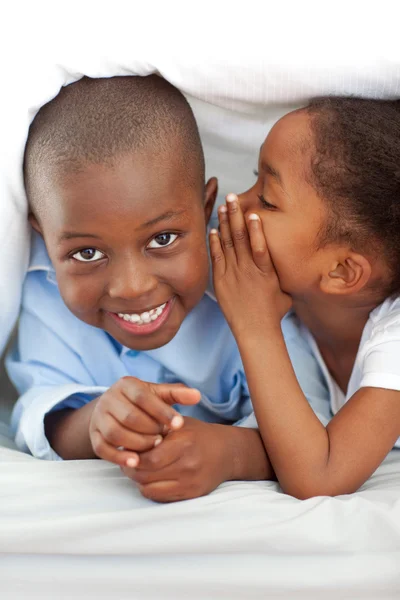 Bedårande liten flicka viskar något till hennes bror — Stockfoto