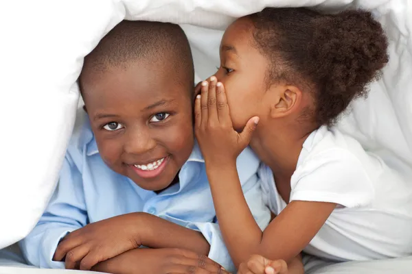 Cute little girl whispering something to her brother — Stock Photo, Image