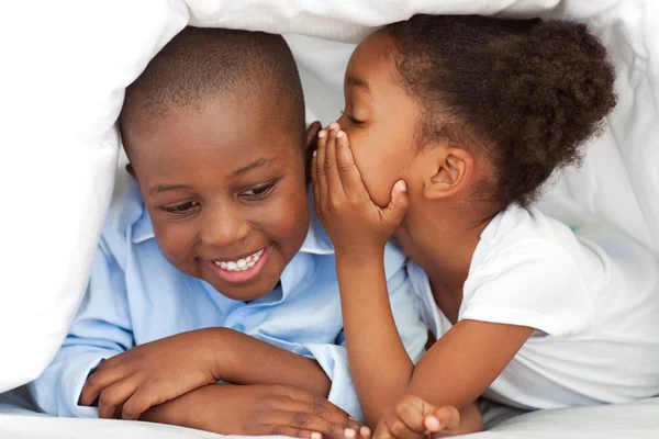Ethnic little girl whispering something to her brother — Stock Photo, Image