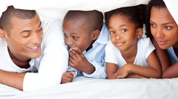 Glada familjen ha roligt liggande på sängen — Stockfoto