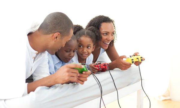 Família animada jogando videogame deitada na cama — Fotografia de Stock