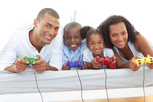 Familia animada jugando videojuego acostado en la cama —  Fotos de Stock